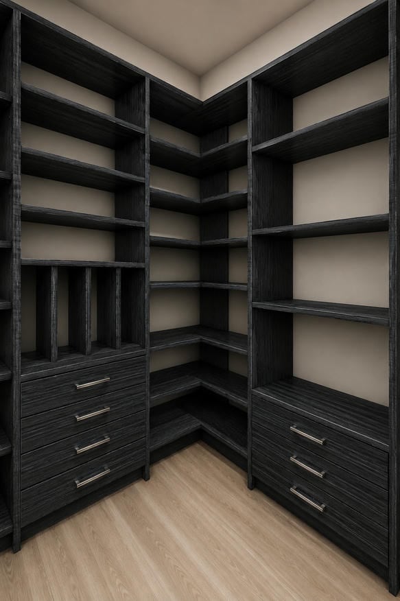 able-closet Empty walk-in closet with dark wood shelves, built-in drawers, and open cubbies in a corner layout. The closet has light-colored walls and a wooden floor.